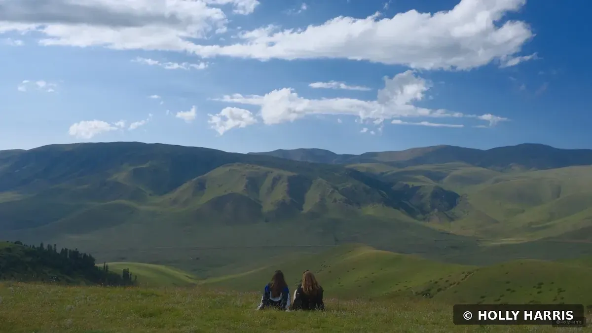 Two people overlooking green mountain valleys in the Tian Shan Mountains of Kazakhstan